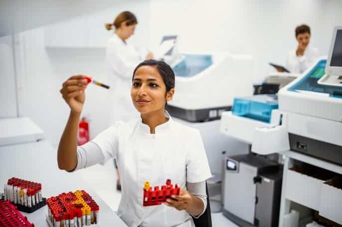 Female lab technician examining blood sample in a medical laboratory, illustrating real-world application of biosensor diagnostics.